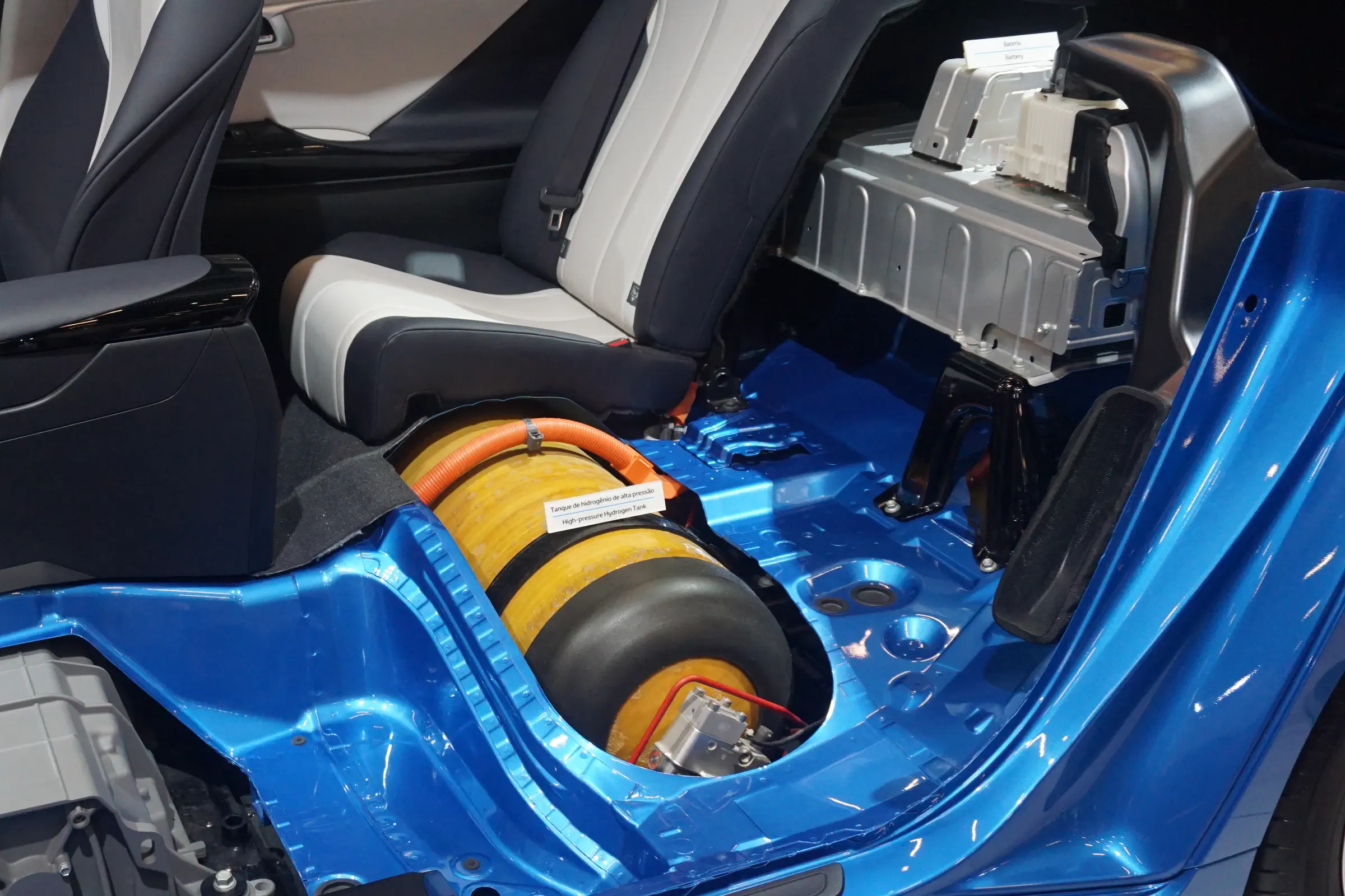 The interior of a car, with seats and and coverings removed to expose a yellow, cylindrical tank.