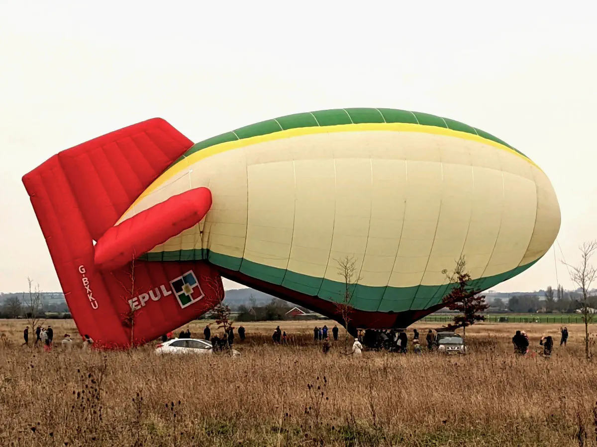 A thermal airship on the ground with a tail that is drooping.
